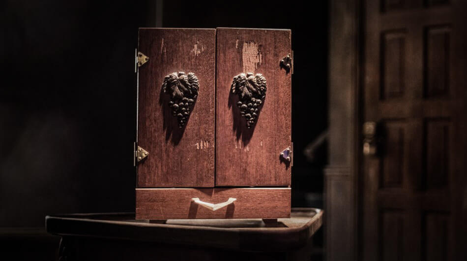 A small wooden cabinet known as a Dybbuk Box with grapevine carvings on its doors. An haunted artifact found in the Zak Bagans Museum.